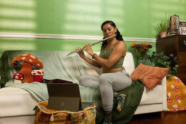 a women sitting on the couch and playing the flute
