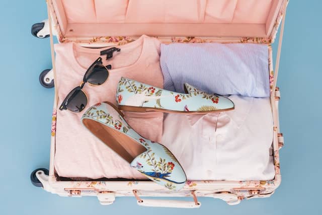 suitcase packed with clothes, shoes and sunglasses