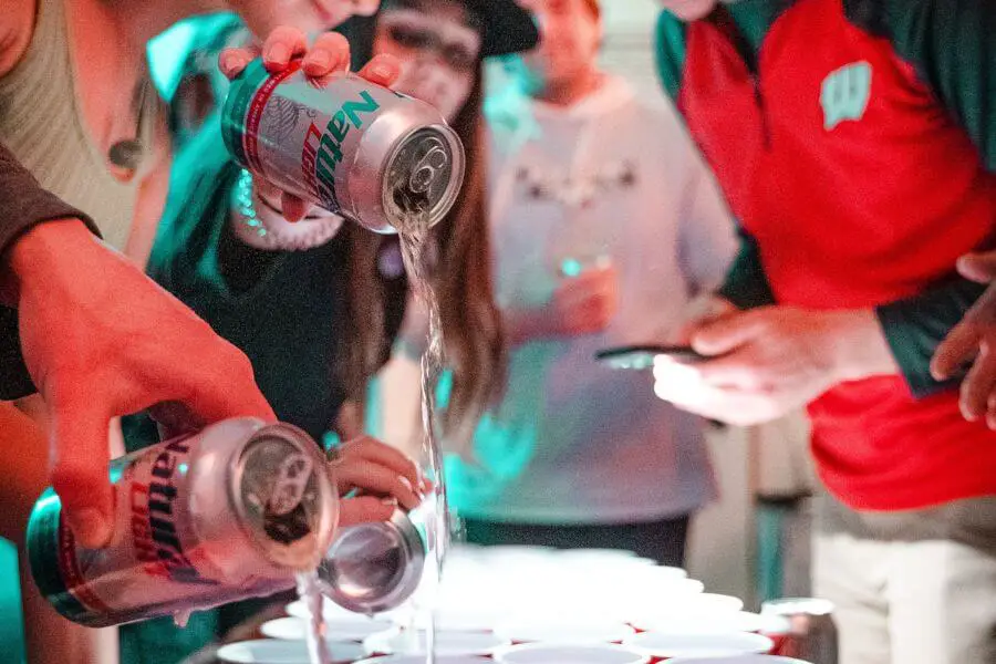 Party goers playing a drinking game by pouring beer into plastic cups
