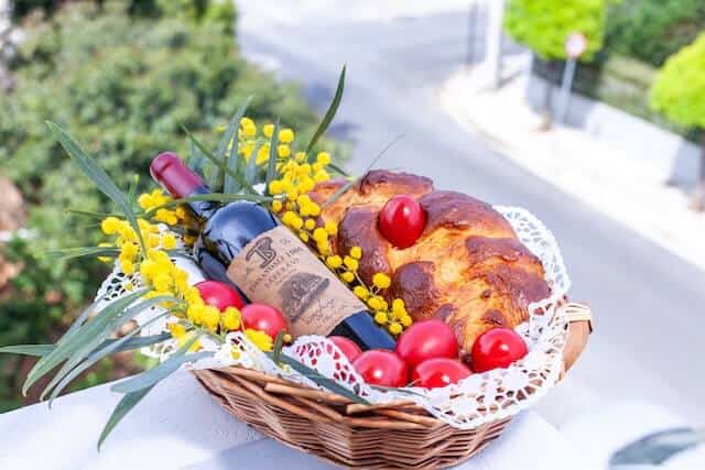 basket decorated with yellow flowers with bread, chery tomatoes and wine