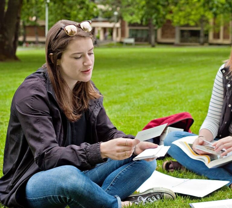 two girls sitting on grass and using active recall to test each other