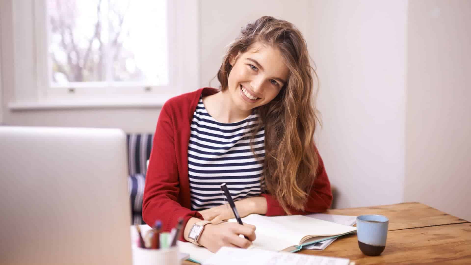 female student writing in her note book while smiling