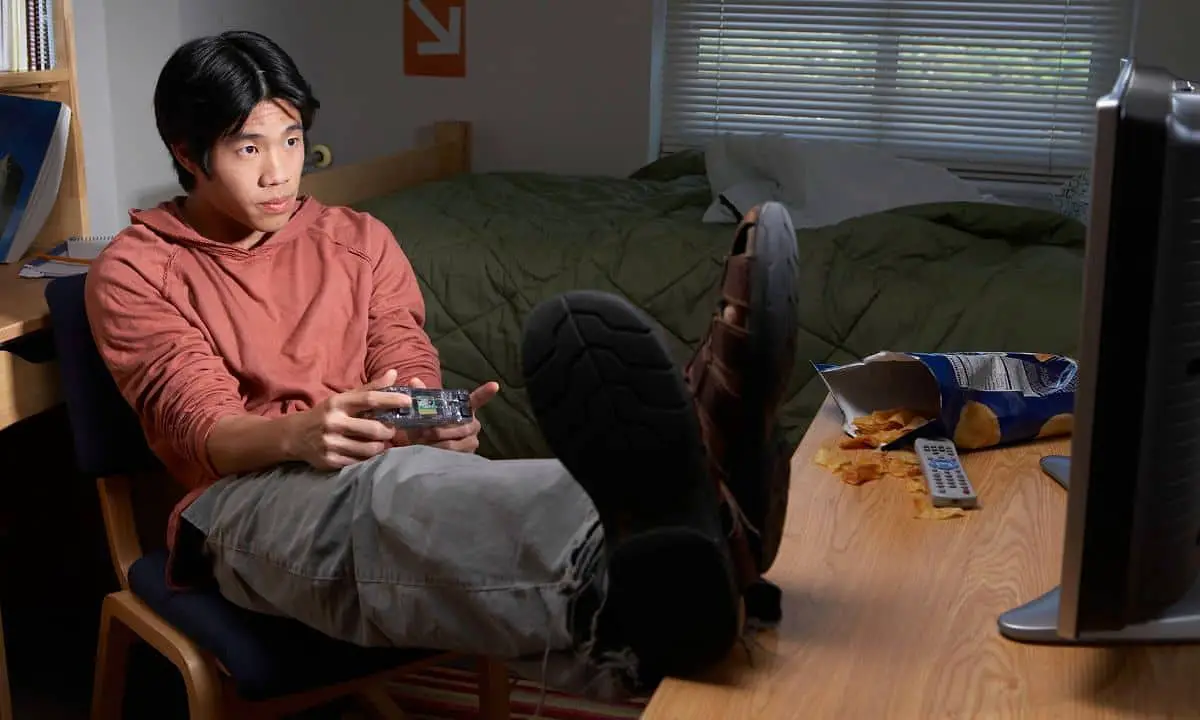 male student playing video game in his dorm room