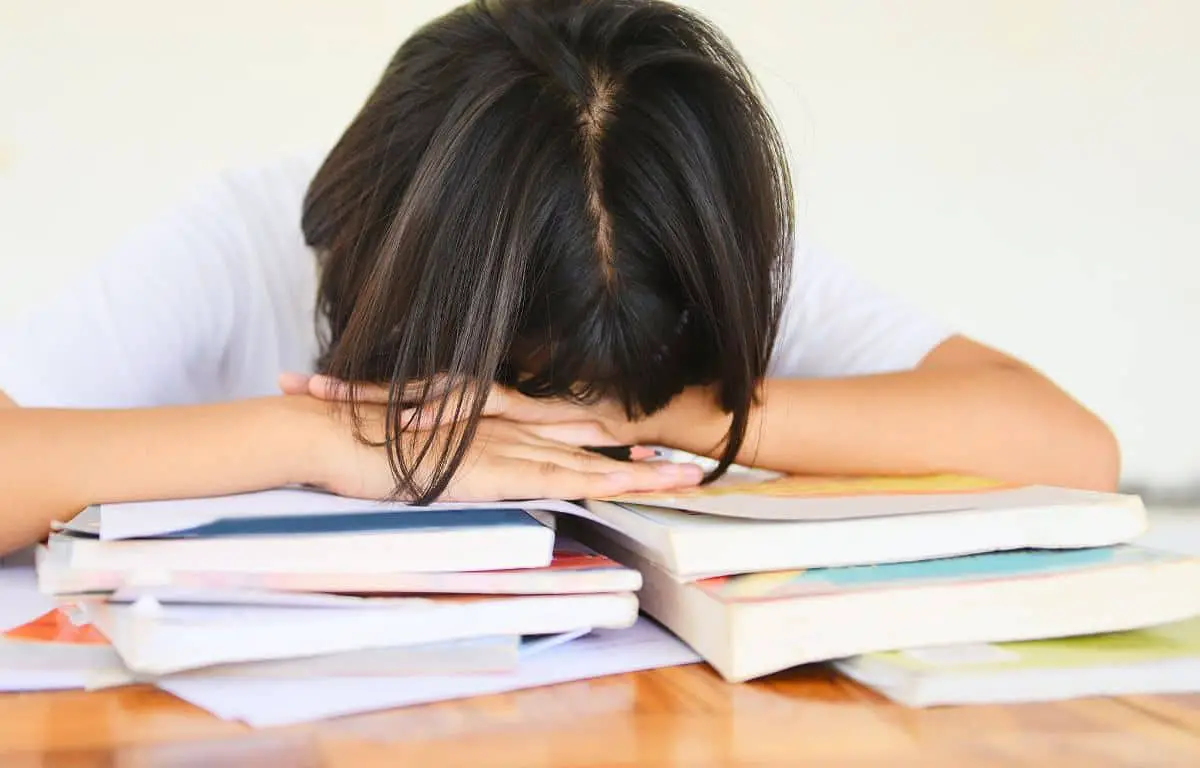 student with head on desk top onto of books after blurting