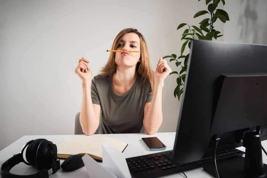 women sitting at desk with pen on her mouth while procrastinating