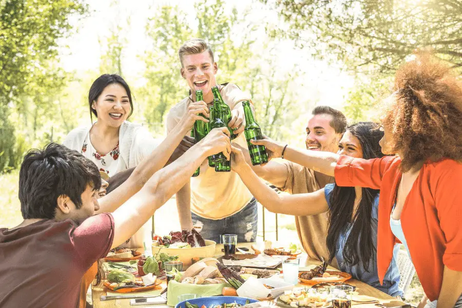 group of college students making a toast and having dinner together while socializing