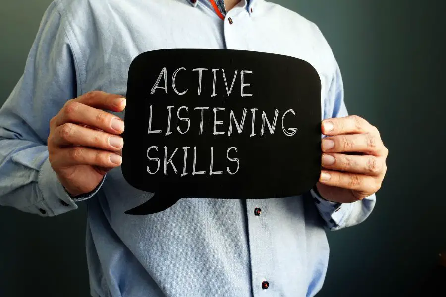 man holding up an active listening skills sign with both his hands.