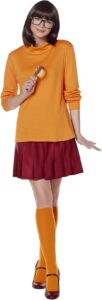 Velma Dinkley costume from *Scooby-Doo*, featuring an orange turtleneck, red pleated skirt, orange knee-high socks, red Mary Jane shoes, black square glasses, and a magnifying glass accessory. Though traditionally a female character, this clever and nerdy ensemble can make a fun and unexpected option for Halloween costumes for guys looking to switch things up.