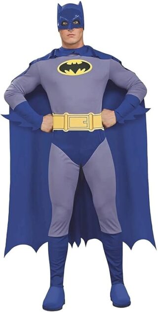 Man dressed in a vintage-style Batman outfit, featuring a gray and blue bodysuit, yellow utility belt, and blue cape with scalloped edges. The costume includes a matching cowl with bat ears and the classic yellow-and-black bat logo on the chest, making it a bold choice for Halloween costumes for guys.